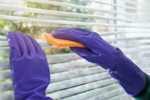 Woman wiping window blinds with rags
